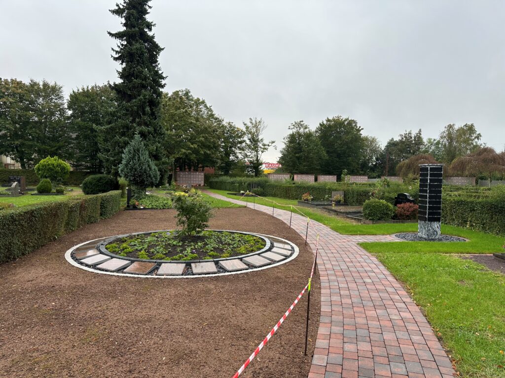 Urnengemeinschaftsgrab mit Namenstafeln (li.) und Urnengrab mit Stele (re.) auf dem Friedhof St. Johann